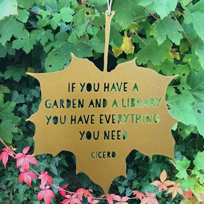 Gold leaf-shaped sign with Cicero quote on a green leafy background